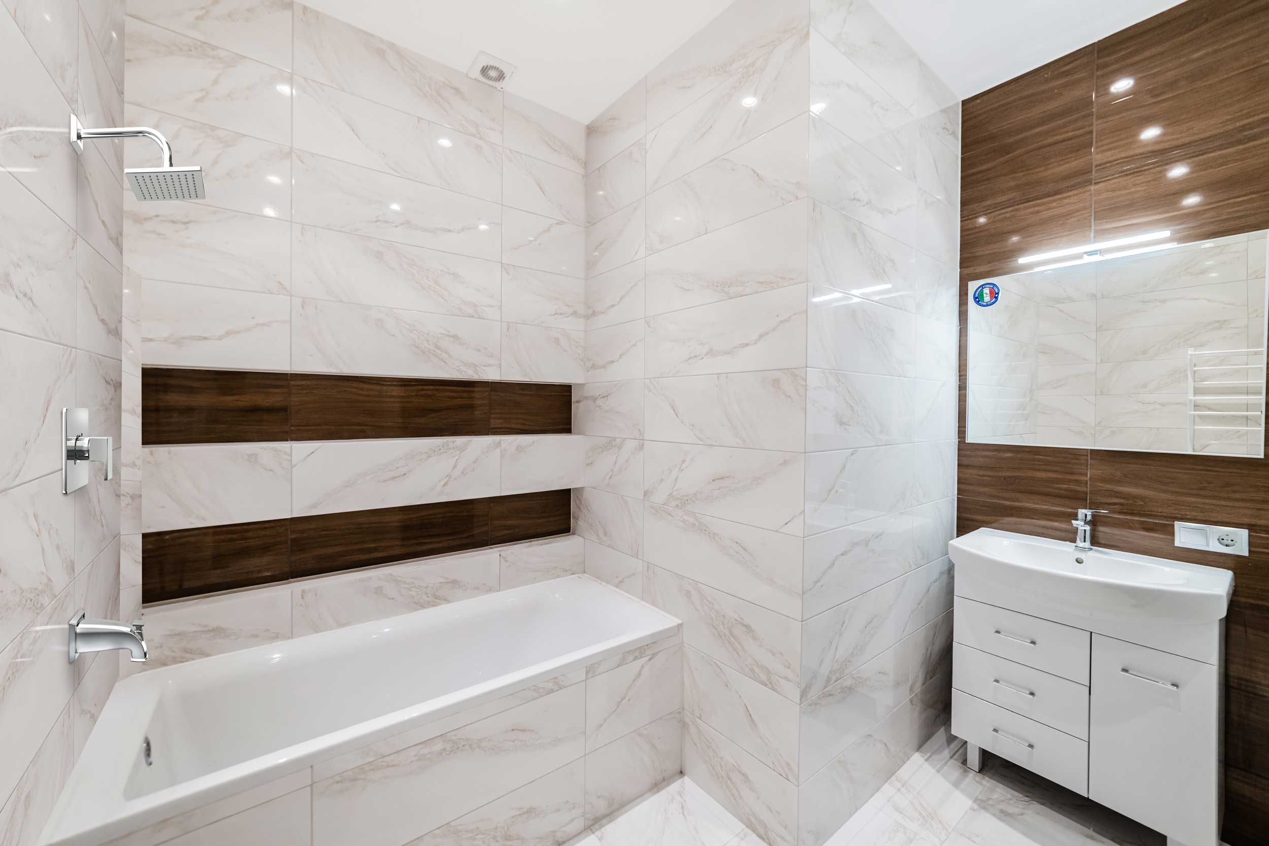 A modern bathroom featuring a stylish combination of white and brown tiles on the walls and floor.