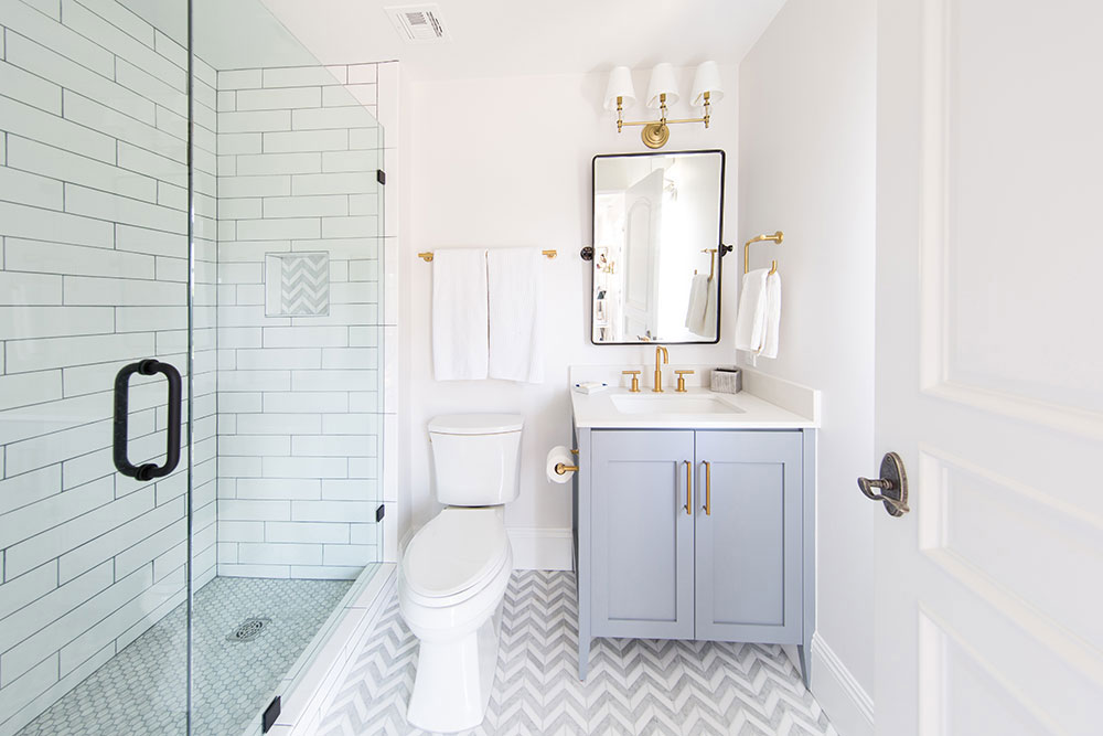 A bathroom featuring white tile and a stylish gray and gold chevron pattern on the walls.